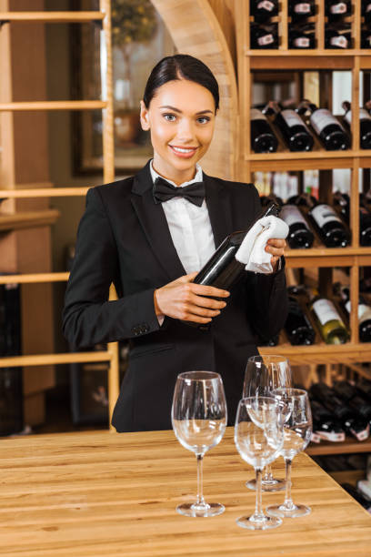 istock smiling female wine steward holding bottle at wine store 1002216320