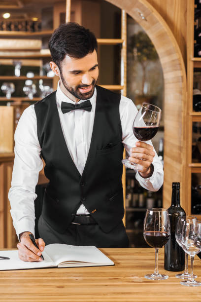 istock smiling young sommelier examining color of wine and making notes at wine store 1002216340
