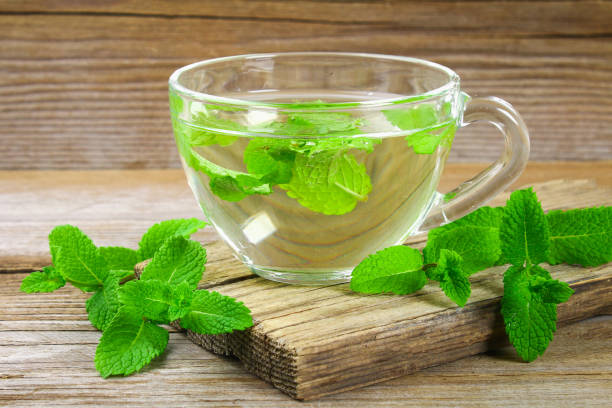 istock Fresh organic mint tea in glass on wooden table. 1002216940