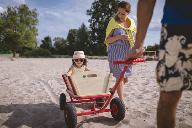 Lovely and cute child with a hat, sitting in a trolley on the beach, enjoying the ride.