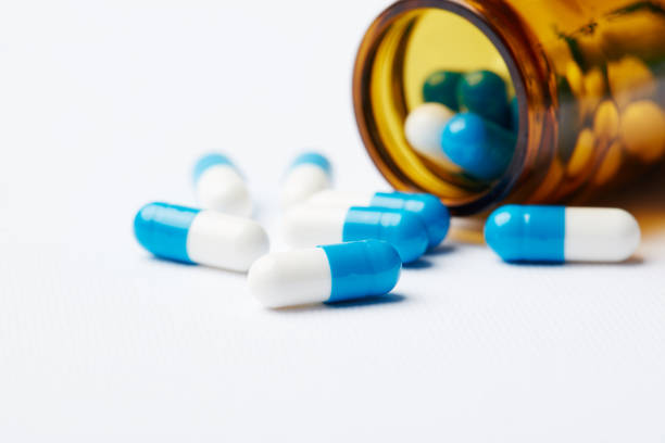 istock Blue-and-white pills scattered on the table from the bottle. 1002222898