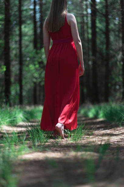 istock Woman in red dress in bare feet on forest path. 1002222904