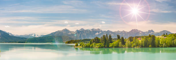 istock Panoramic scene in Bavaria with alps mountains mirroring in lake Forggensee 1002223704