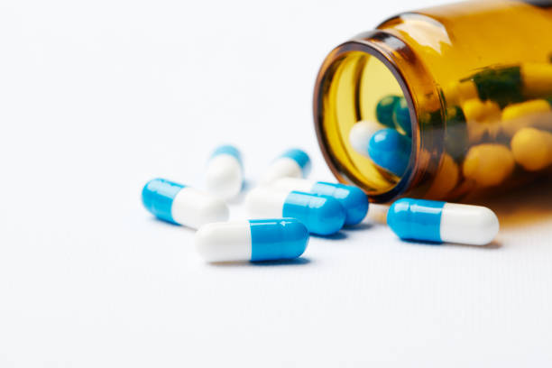 istock Blue-and-white pills scattered on the table from the bottle. 1002223754
