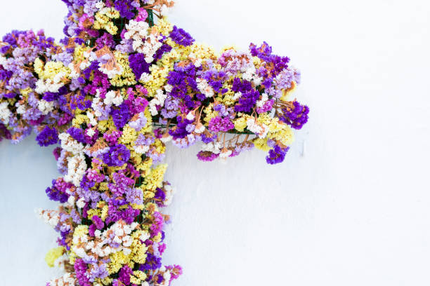 istock Cross decorated with colorful flowers on white wall 1002233634
