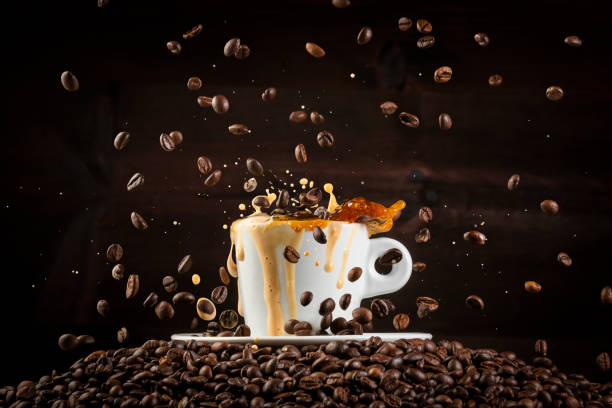 istock Coffee beans splashing on white cup with dark background 1002235298