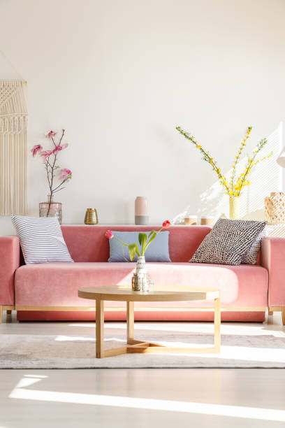 almofadas no sofá vermelho e mesa de madeira no interior da sala de estar com flores. foto real - pillow cushion red textile - fotografias e filmes do acervo