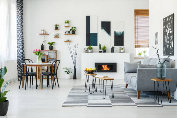 istock Black chairs at dining table in bright living room interior with grey sofa near fireplace. Real photo 1002239254