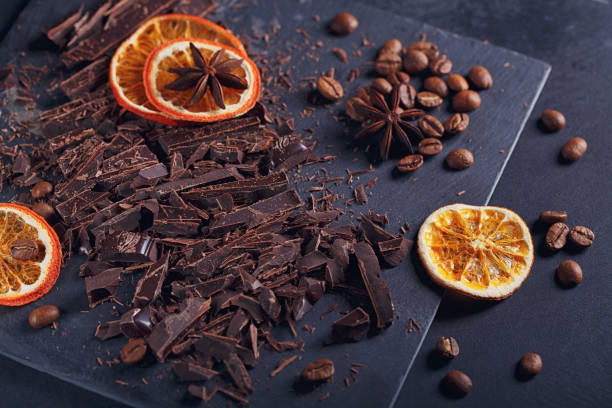 istock Dark chopping chocolate, black roasted coffee beans, dried lemon slices on dark background 1002260732