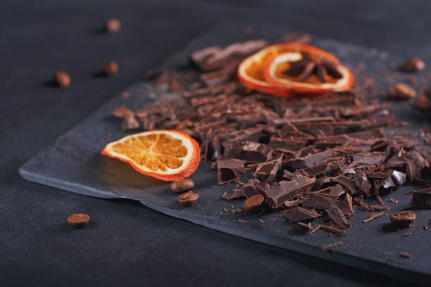 istock Dark chopping chocolate, black roasted coffee beans, dried lemon slices on dark background 1002260740
