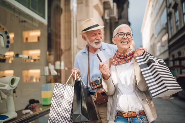 coppia sorridente in possesso di borse della spesa e una carta di credito - spending money foto e immagini stock