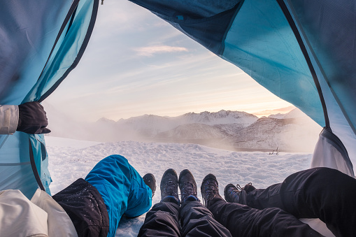 Group of climber are inside a tent with open for view of blizzard on snow mountain
