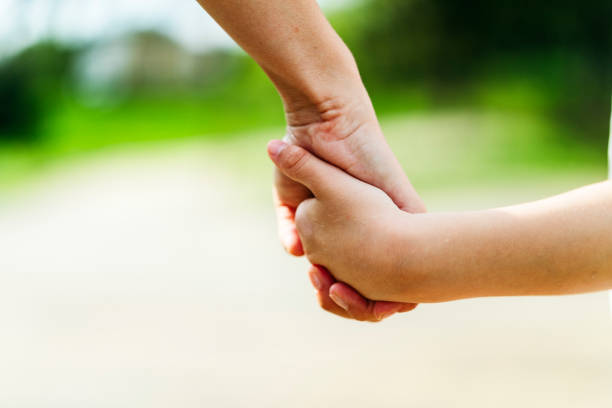 istock Child holding hands with mother closeup 1002270804
