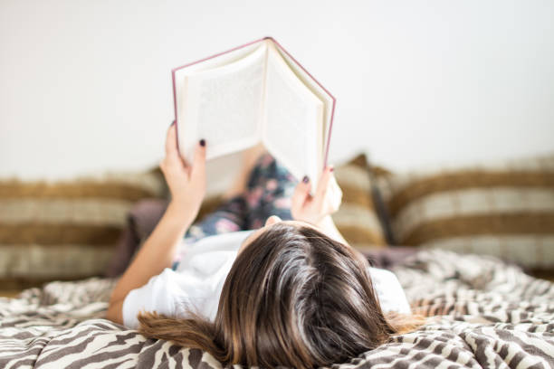 istock Cute caucasian girl lying in her bed and reading a book 1002271616