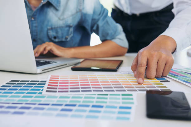istock Two young interior design or graphic designer working on project of architecture drawing with work tools and color swatches, colour chart in digital tablet at workplace 1002279108