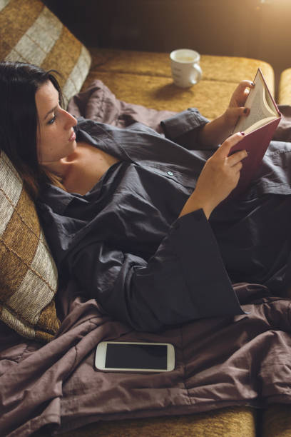 istock Cute caucasian girl lying in her bed and reading a book 1002281082