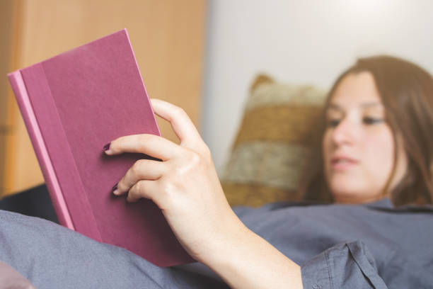 istock Cute caucasian girl lying in her bed and reading a book 1002284114