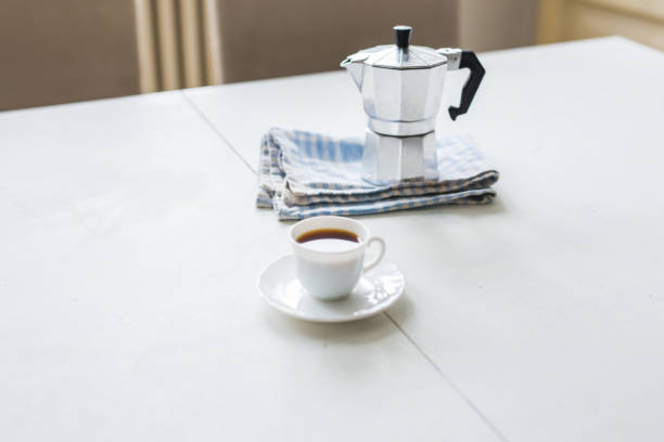 istock Cup of coffee, coffee kettle on a white table 1002312076