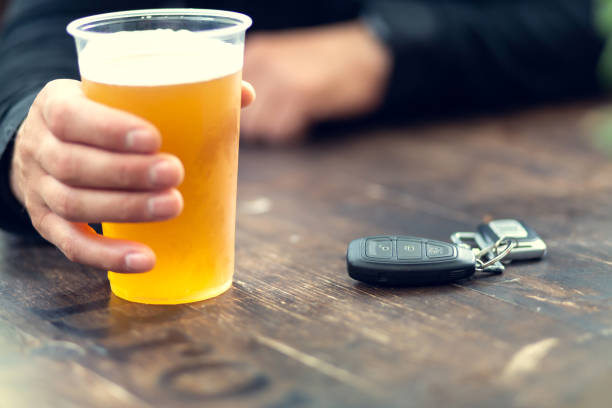 человек пьет пиво и ключи от машины на столе. концепция вождения автомобиля после употребления алкоголя. - designated driver стоковые фото и изображения