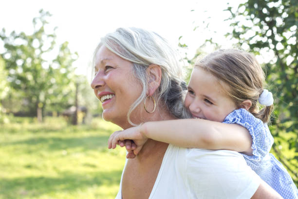 Little girl on a piggy back ride with her grandmother stock photo
