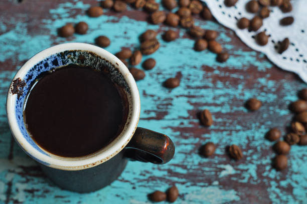 istock A cup of coffee and coffee beans on blue surface 1002320414