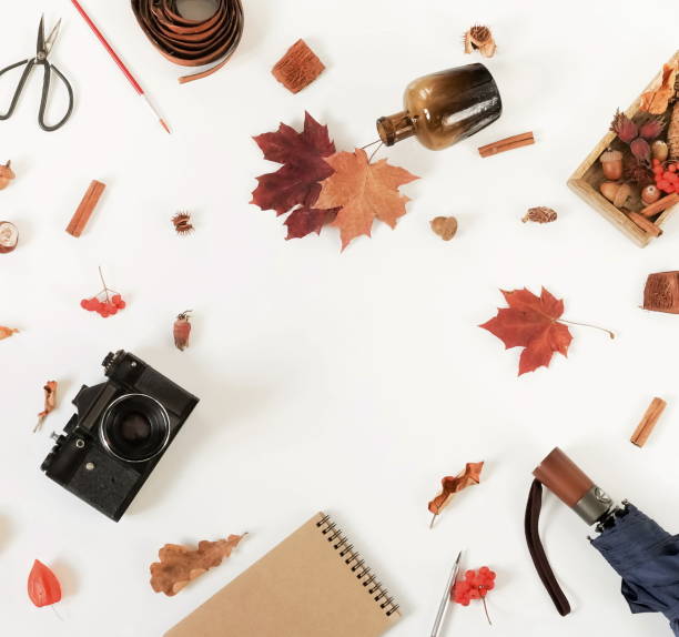 istock Autumn composition background. Artist home office desk workspace , autumn leaves, old camera, notebook, umbrella on  white background. Flat lay, top view creative minimal mock up template.  Copy space 1002329508