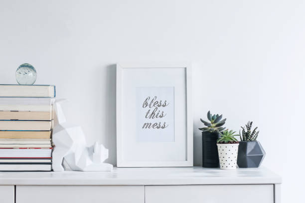 istock Creative cupboard with mock up poster frame, cat figures, cacti and books. Modern and minimalistic concept of space. 1002339788