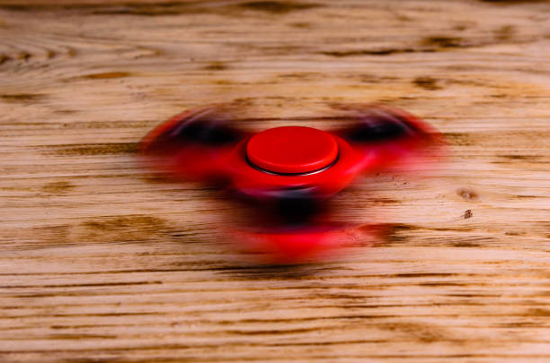 istock Red fidget spinner rotates on wooden desk 1002342888