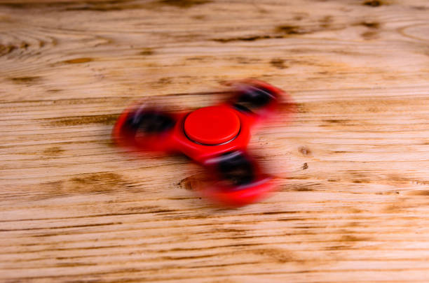 Red fidget spinner rotates on wooden desk