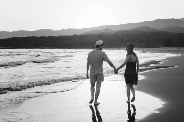 Photo of young lovely couple walking on windy coast line. Back horizontal view