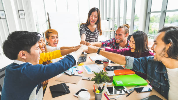 Multiethnic diverse group office coworker, business partner join hands by fist bump in modern creative office. Colleague partnership teamwork, startup company, or project achievement celebrate concept stock photo