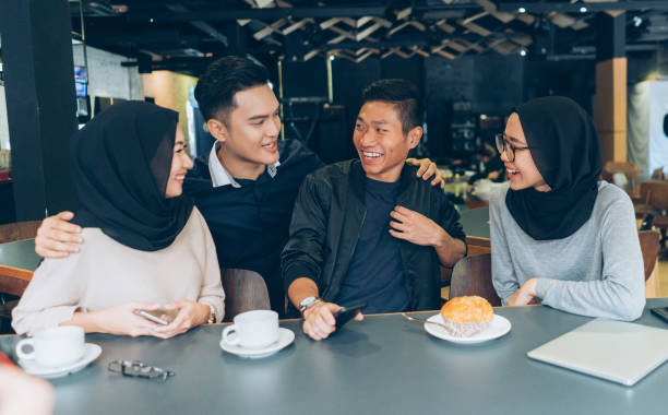 Young Malaysian couples are talking and drinking coffee in a cafeteria