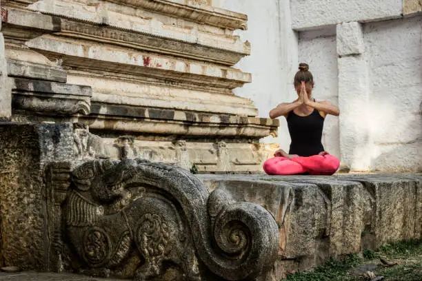 Yogi woman in padmasana pose with hands together on face in Srirangapatna temple, Karnataka, India