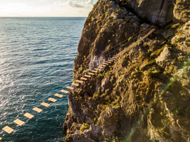 vista aérea del puente de cuerda en una puesta de sol en montaña hora dorada cerca de la costa del mar - carrick a rede fotografías e imágenes de stock