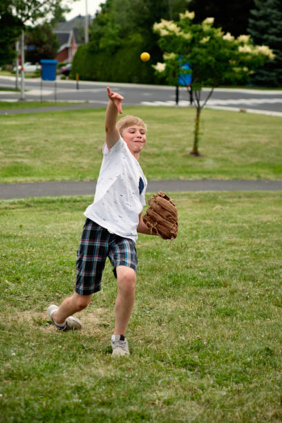 istock Young boy playing baseball in suburb park. 1002438254