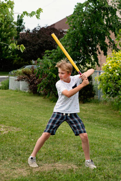 istock Young boy playing baseball in suburb park. 1002438386