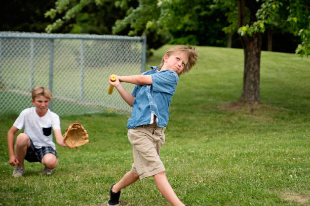 istock Brothers playing baseball in suburb park. 1002439888