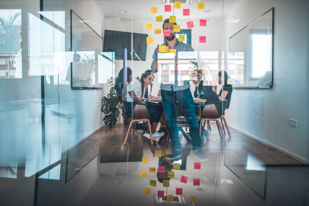 Businessman sticking adhesive note on glass wall