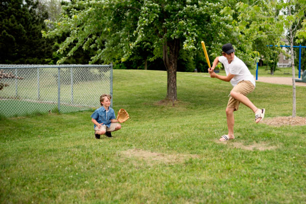 istock Brothers playing baseball in suburb park. 1002440006