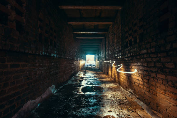 istock Light and exit in end of dark long brick abandoned industrial tunnel or corridor or sewer channel, way to freedom concept 1002456444