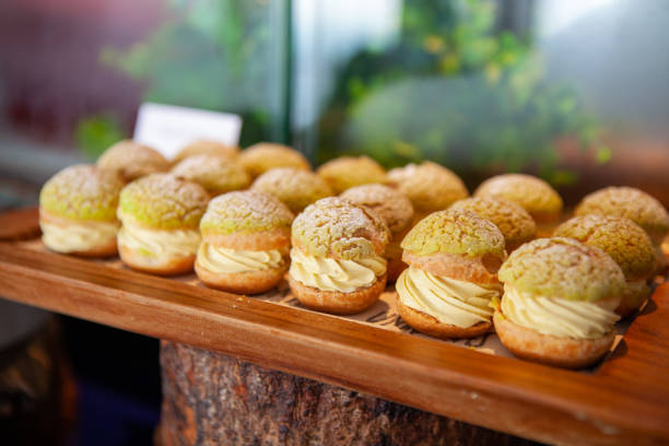 Tasty Mini Green Tea Choux au Craquelin or French Crunchy Cream Puff. Tasty Mini Green Tea Choux au Craquelin or French Crunchy Cream Puff filled with delicious and creamy Chantilly Cream on a wooden tray. Selective focus. choux pastry photos stock pictures, royalty-free photos & images