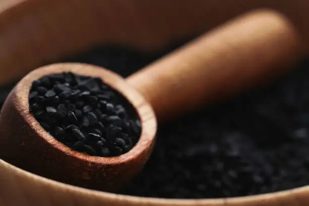 Nigella seeds with wooden scoop in a bowl