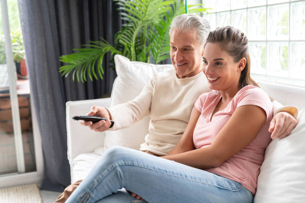 istock Loving couple watching television at home 1002488816