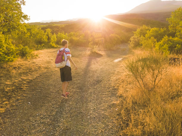 istock young man with backpack walking on a mountain road tourist nature concept 1002496694