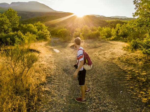 istock young man with backpack walking on a mountain road tourist nature concept 1002496738
