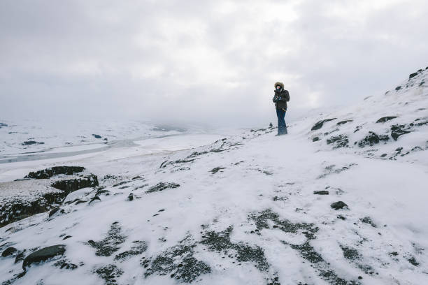 istock Man Standing On Snowcapped Mountain Against Sky 1002497232