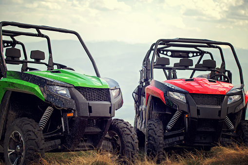 Friends driving off-road with quad bike or ATV and UTV vehicles.