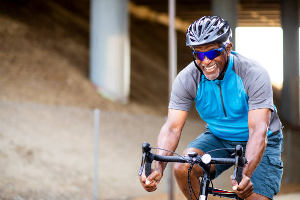 senior black man riding bike on trail - blue helmets imagens e fotografias de stock