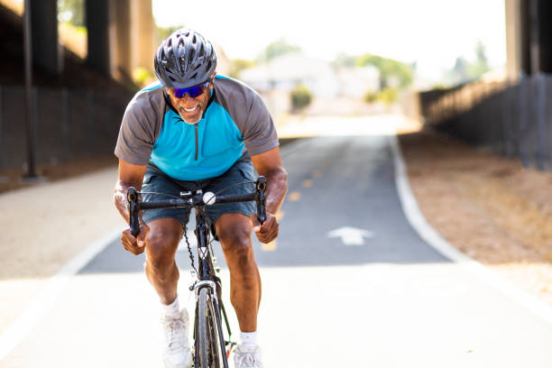 senior homme noir racing sur un vélo de route - cycling senior adult sports helmet men photos et images de collection