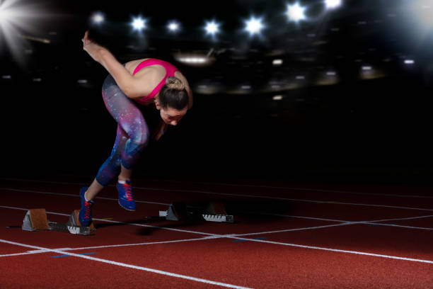 istock woman sprinter leaving starting blocks on the athletic track. exploding start on stadium with reflectors 1002518768